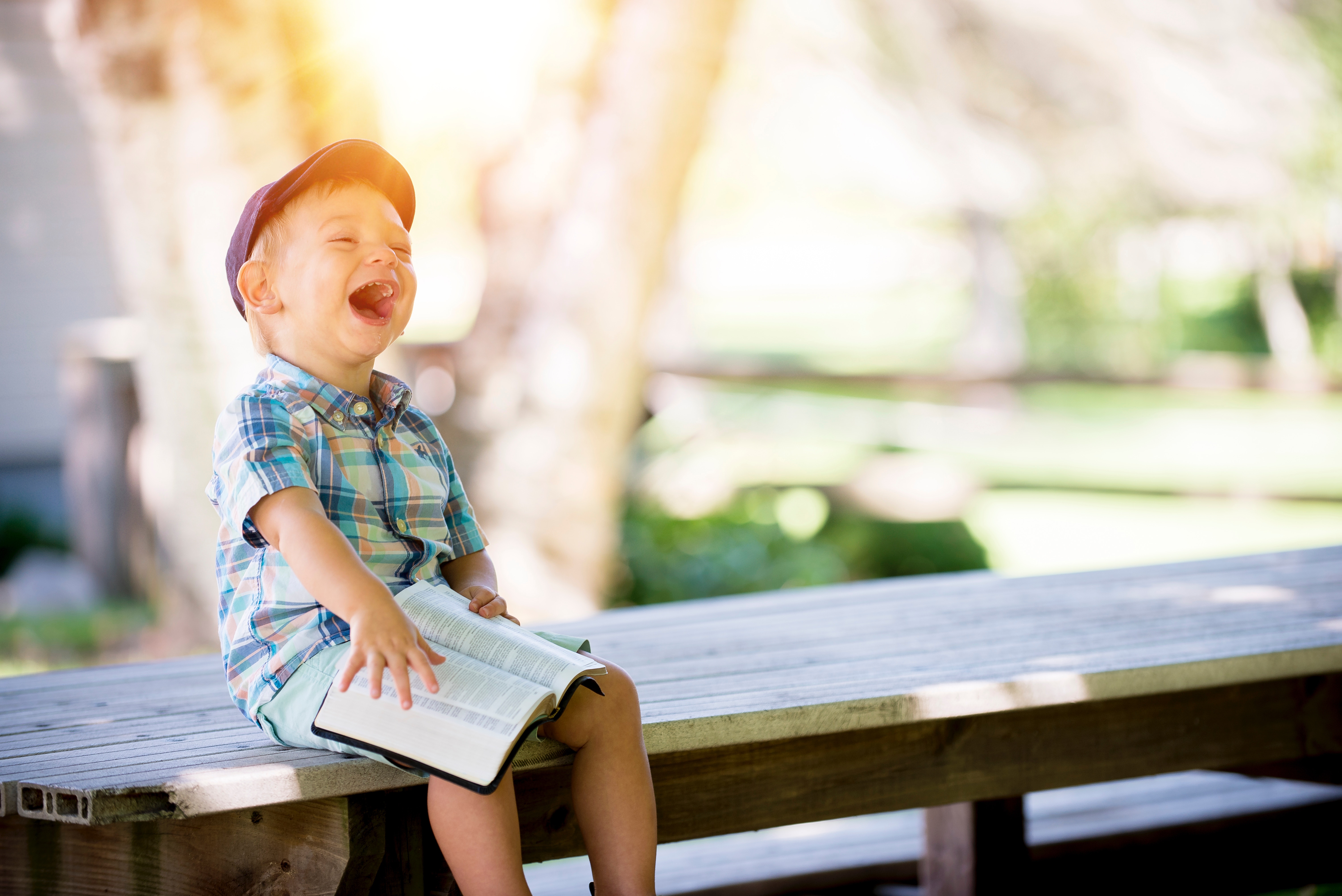little boy laughing with bible in lap