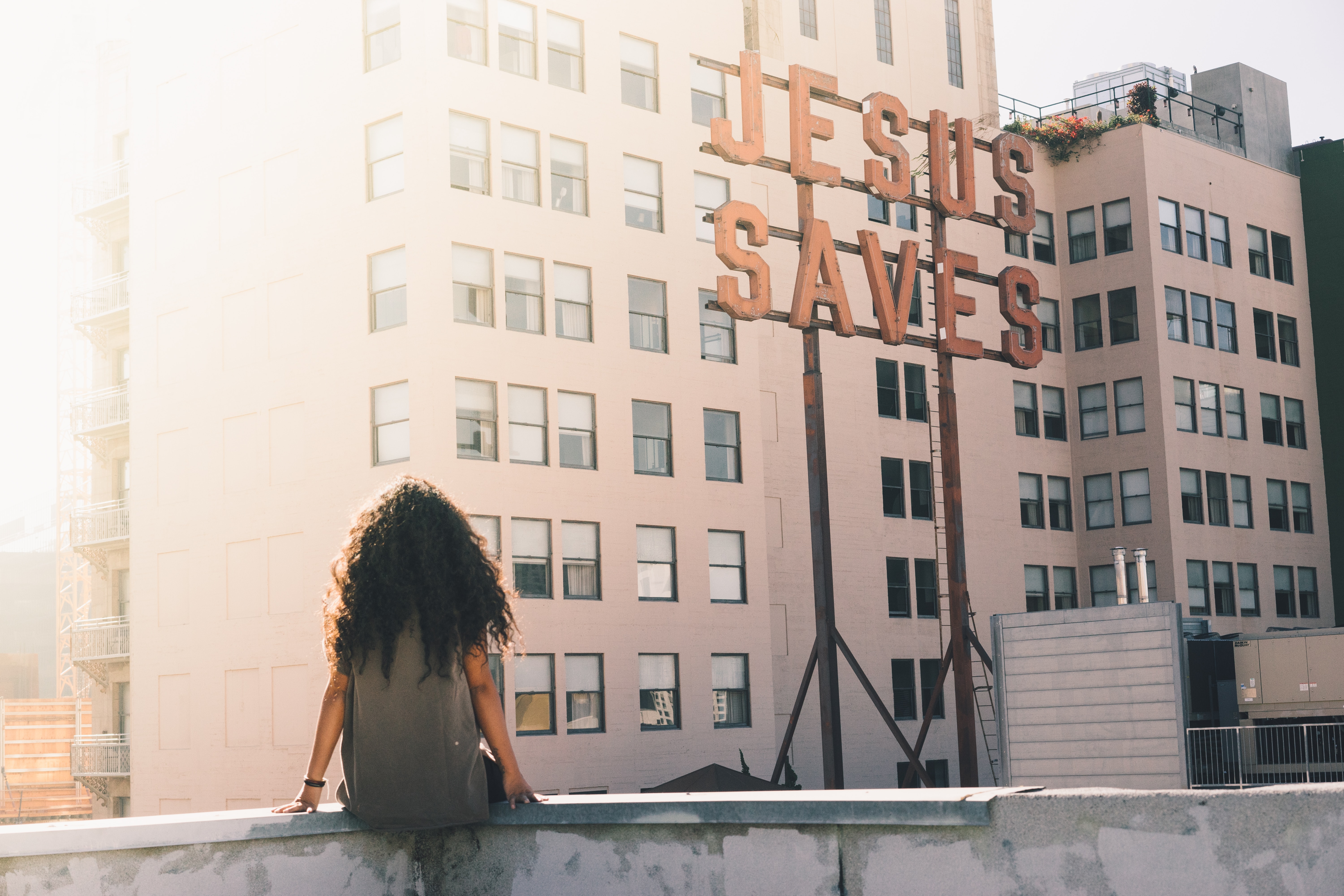 Jesus saves on a building with woman sitting on ledge