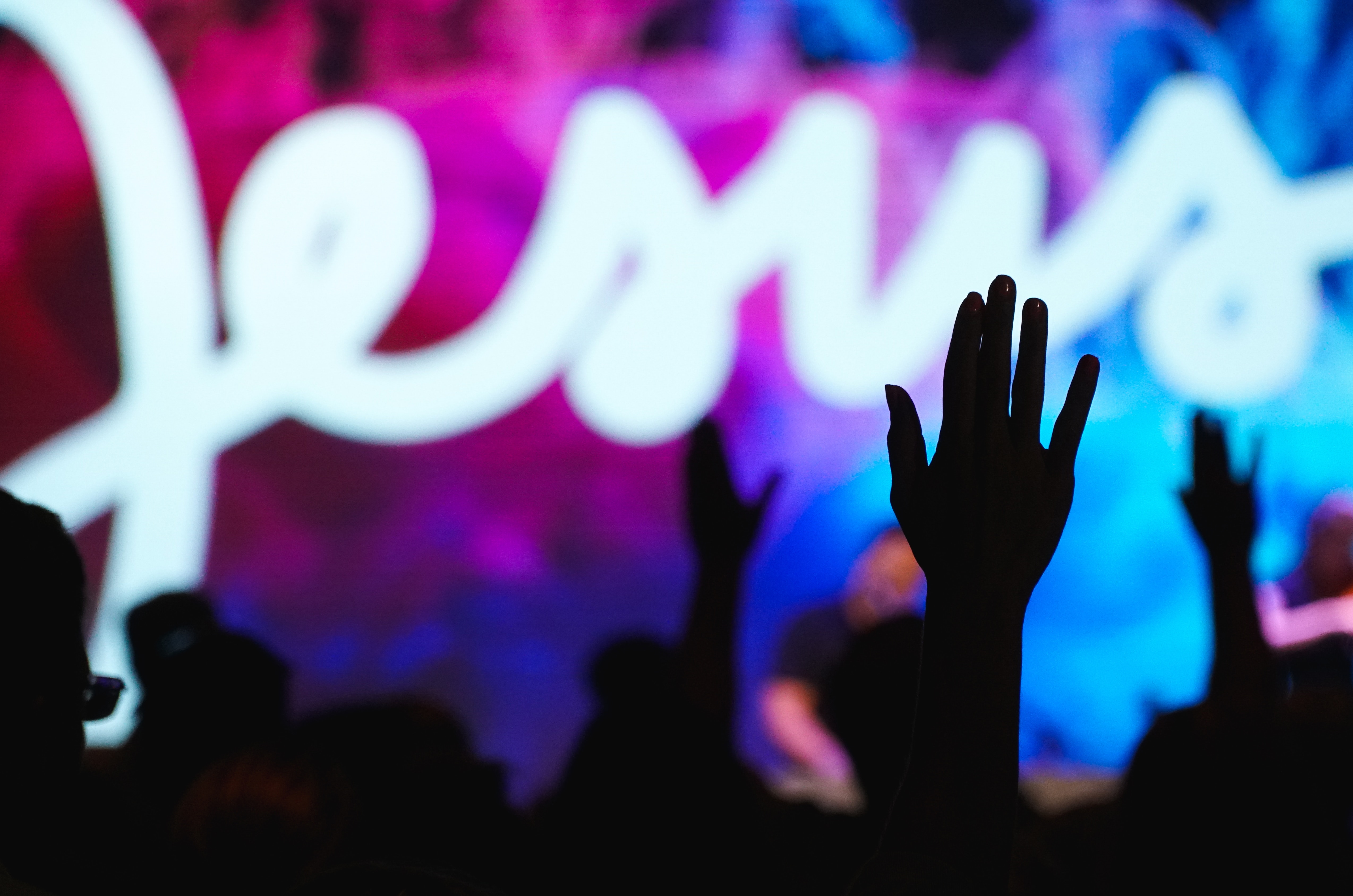 The word Jesus in background with hand raised