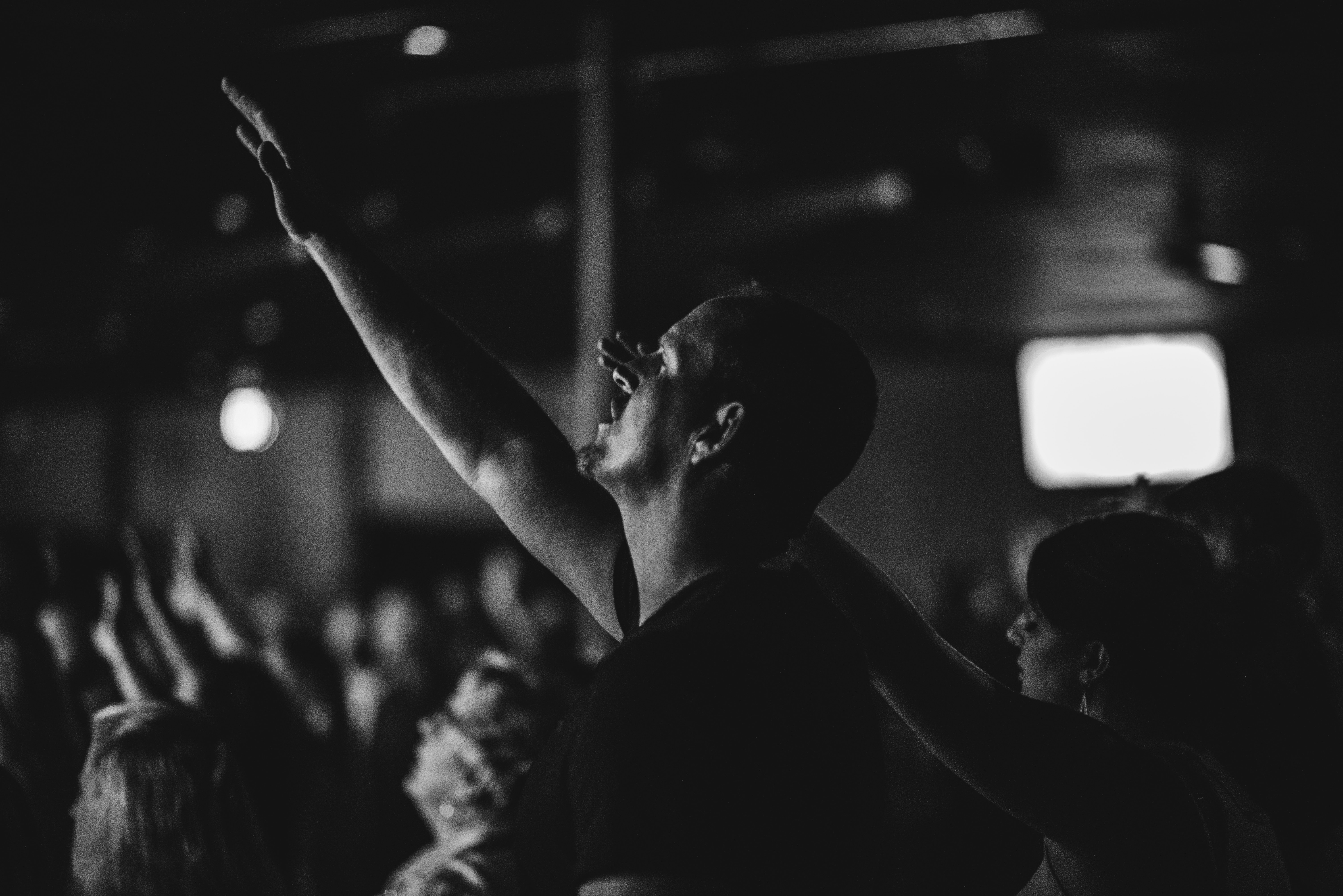 man with eyes closed with hand raised in worship