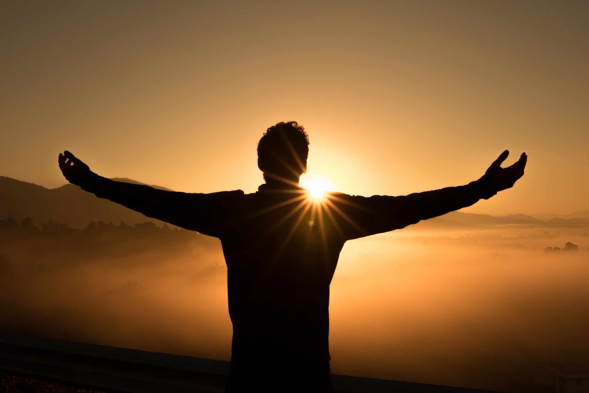 man worshiping facing the sunset